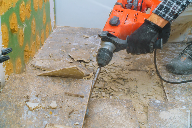 Removal of old floor during a renovation of housing from demolition hammer, fragments of ceramic tiles